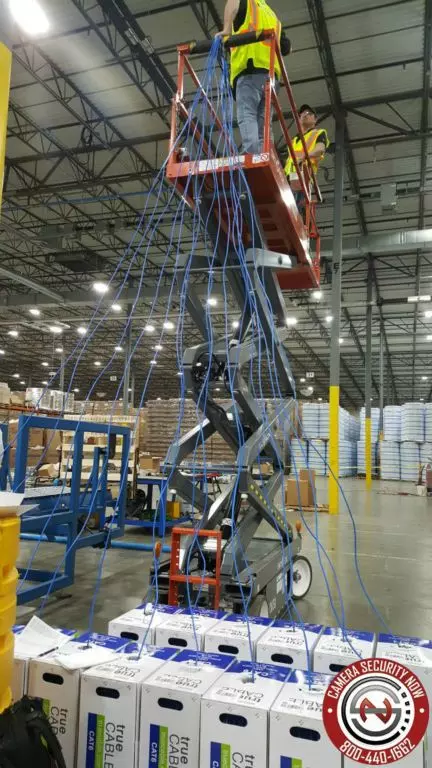 Technicians on a scissor lift pulling cabling for security camera installation