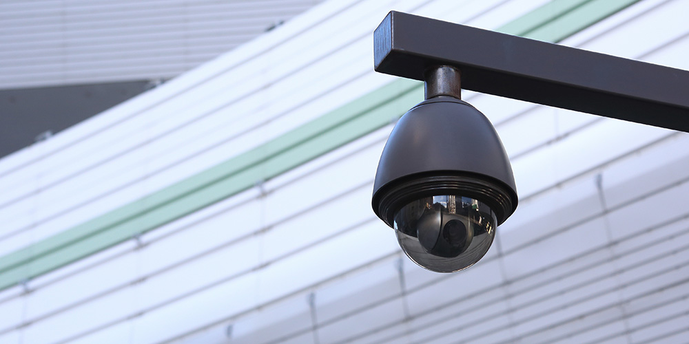 A security camera mounted on a horizontal pole on the exterior of a building