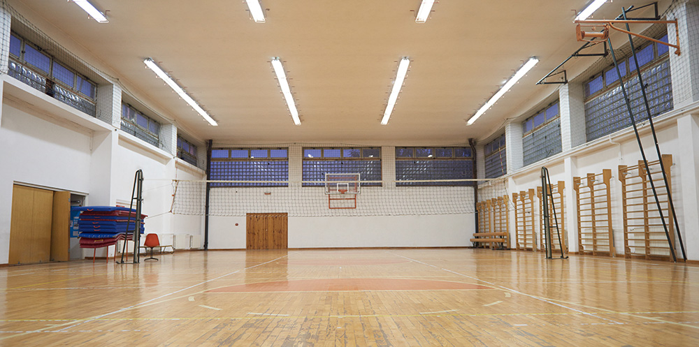 An empty school gymnasium, with various sporting equipment ready for use