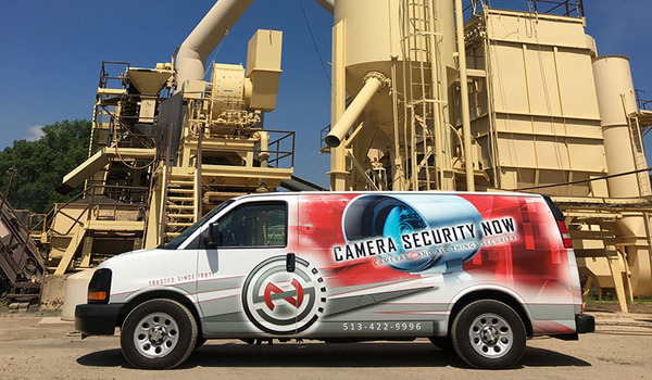 The Camera Security Now work van parked in front of manufacturing machinery