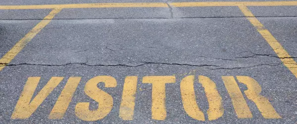 An empty parking space labeled for visitor parking