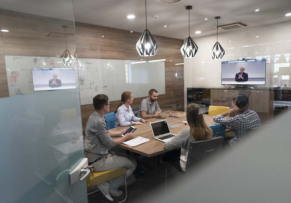 A group of people around a table on a video conference